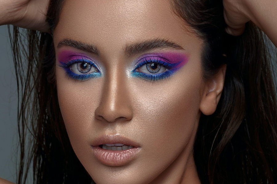 A woman wearing blue and purple eye makeup