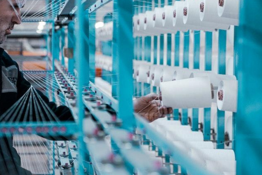 A worker inspecting thread rolls inside a factory