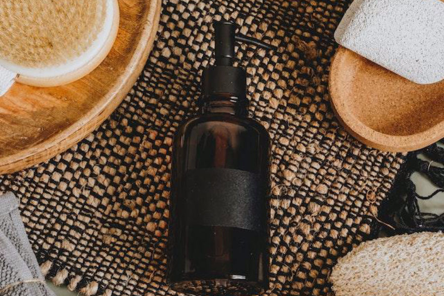 Black bottle on a table with other beauty items
