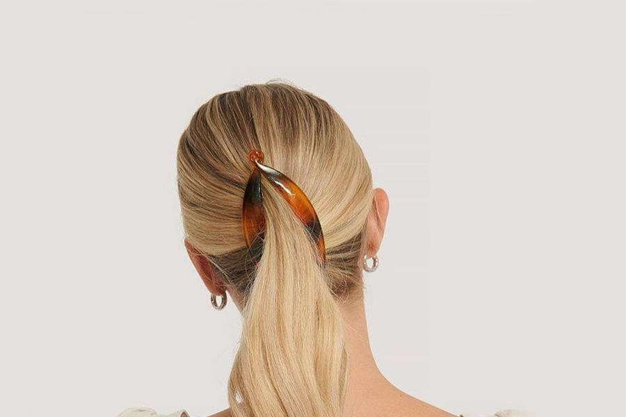 Blond woman styling a ponytail with a banana clip