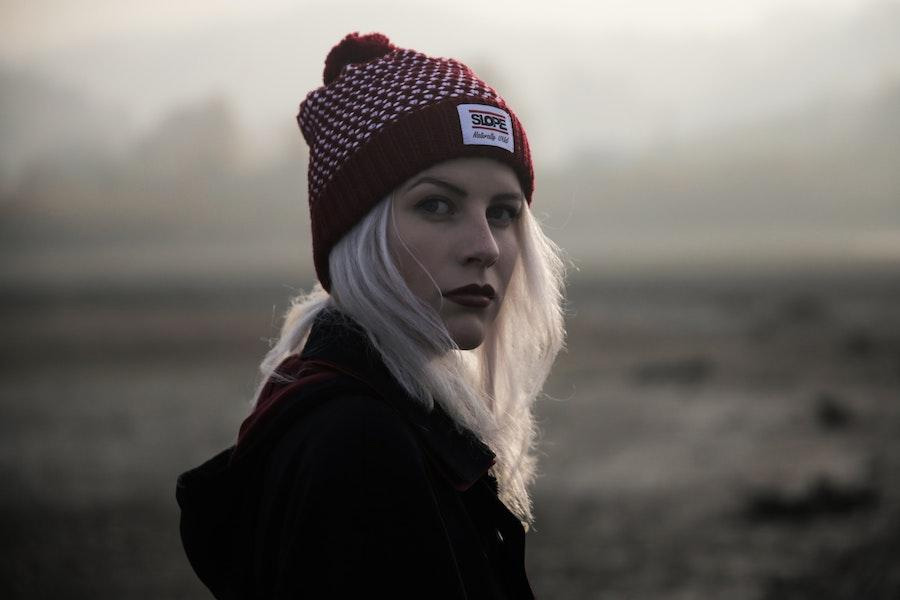 Blonde woman posing with a red beanie