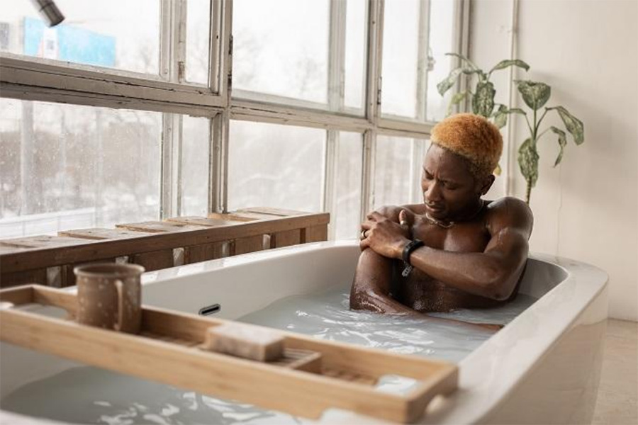 Dark-skinned man in a bathtub using a solid soap