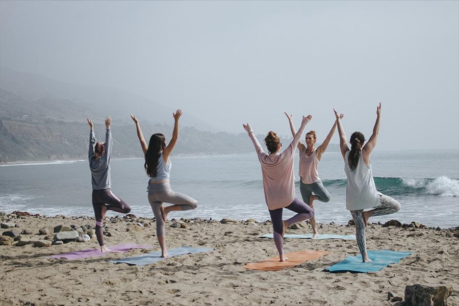 group practicing yoga together on the beach