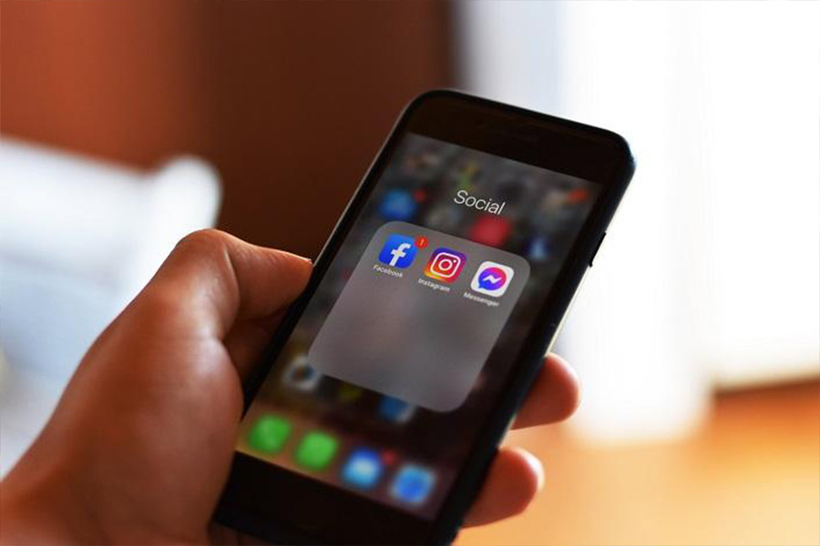 A hand holding a phone with social media app icons on the screen