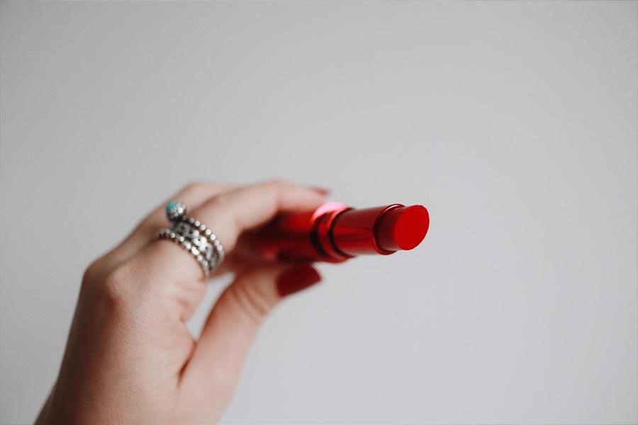 Hand holding a red tube of lipstick