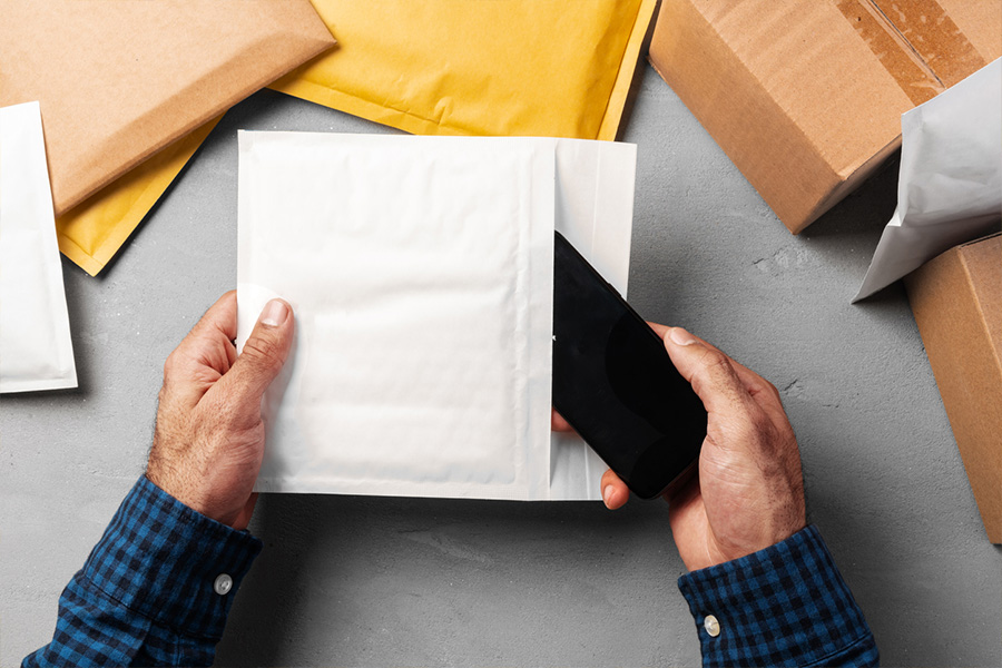 Male hands packing yellow bubble envelopes for shipping
