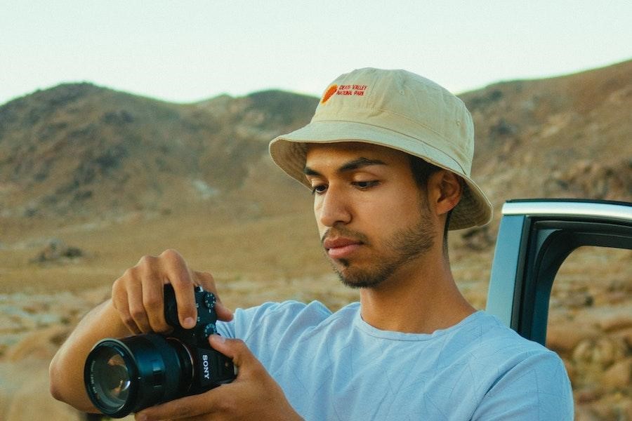 Man holding a camera while rocking a white bucket hat