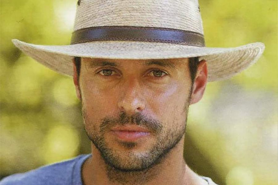 Man in a blue top wearing a panama straw hat