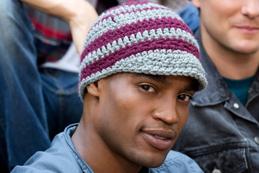 Man in a crowd wearing a multi-colored crochet hat