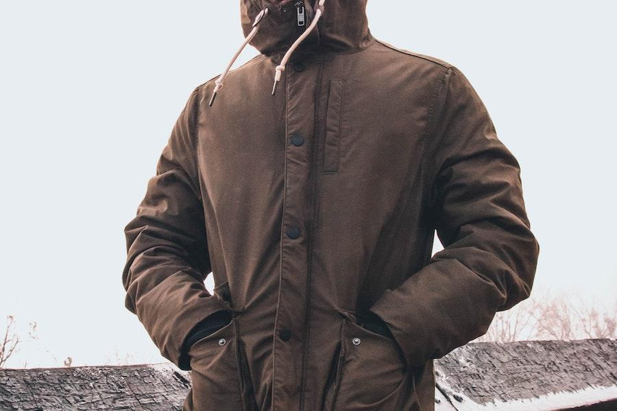 man putting hands in the pockets of a brown windbreaker