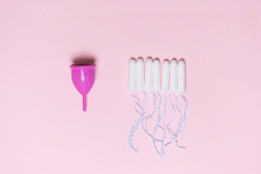 Menstruation cups and tampons on a pink background