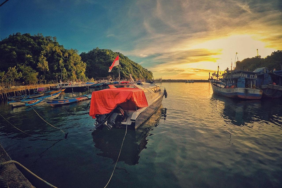 Motorboat with Indonesian flag near dock during sunset