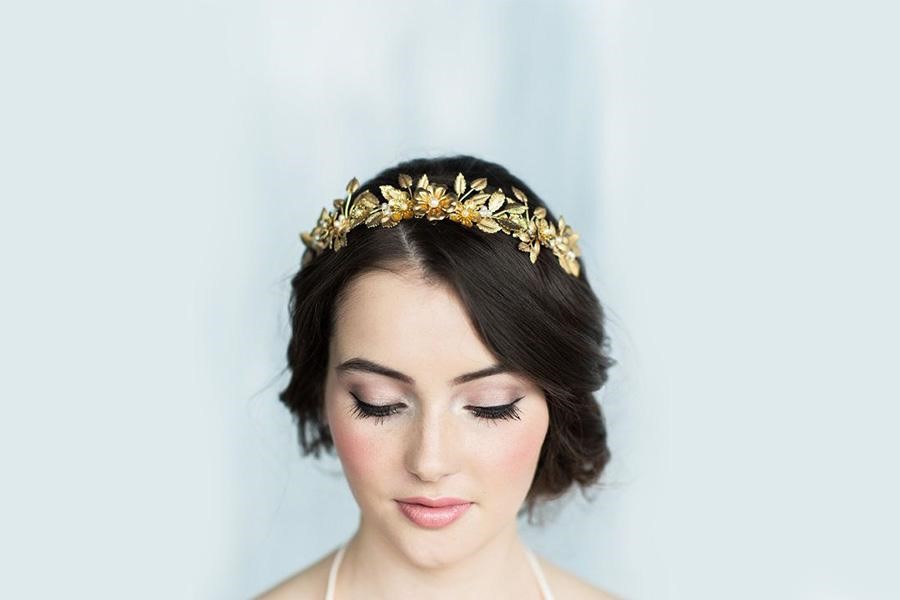 Regal-looking woman pulling off a golden laurel headband