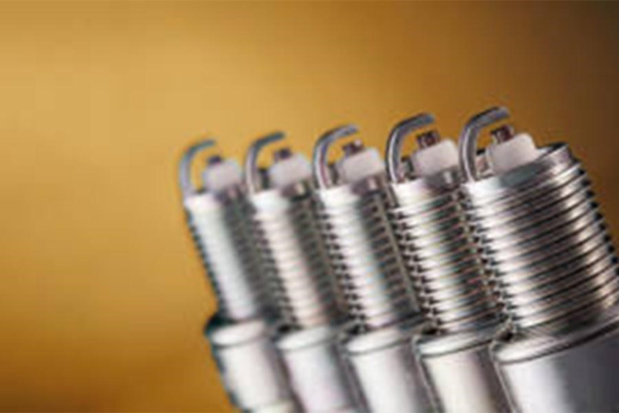 Two sets of motorcycle spark plugs on a brown background.