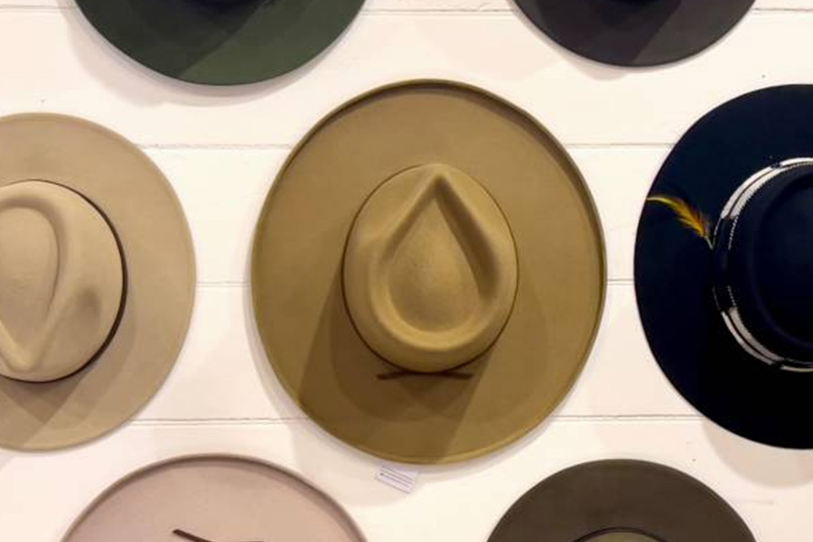 variety of felt cowboy hats hung on a paneled wall
