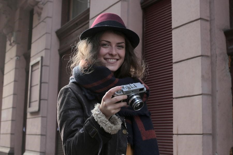 Woman holding a camera while rocking a trilby