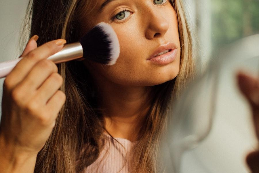 Woman holding a makeup brush while applying cosmetics