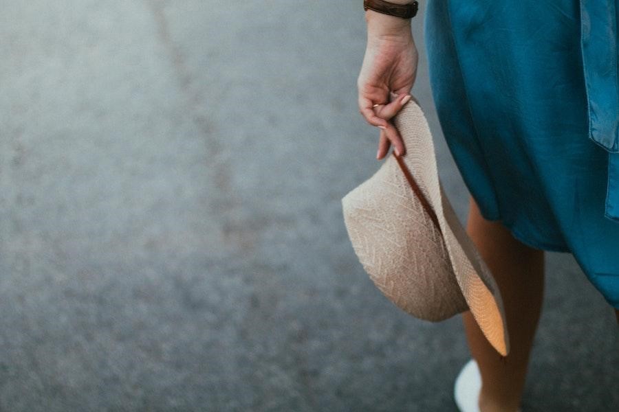 Woman holding a straw hat while walking