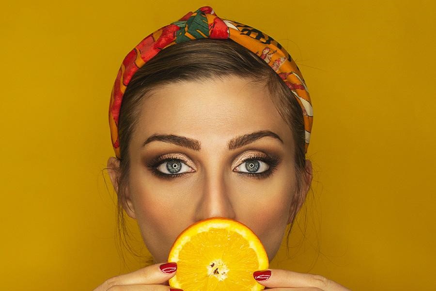 Woman holding an orange in a scarf headband