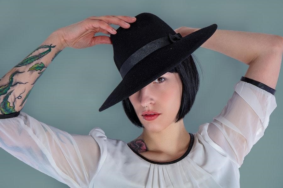 Woman in a white long-sleeve with a black fedora