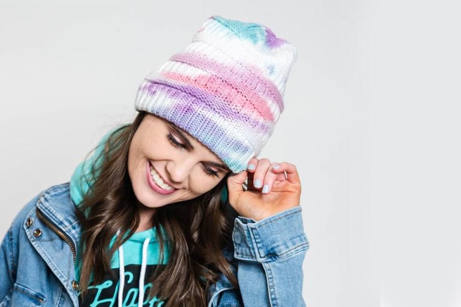 Woman posing with a colorful tie-dye beanie
