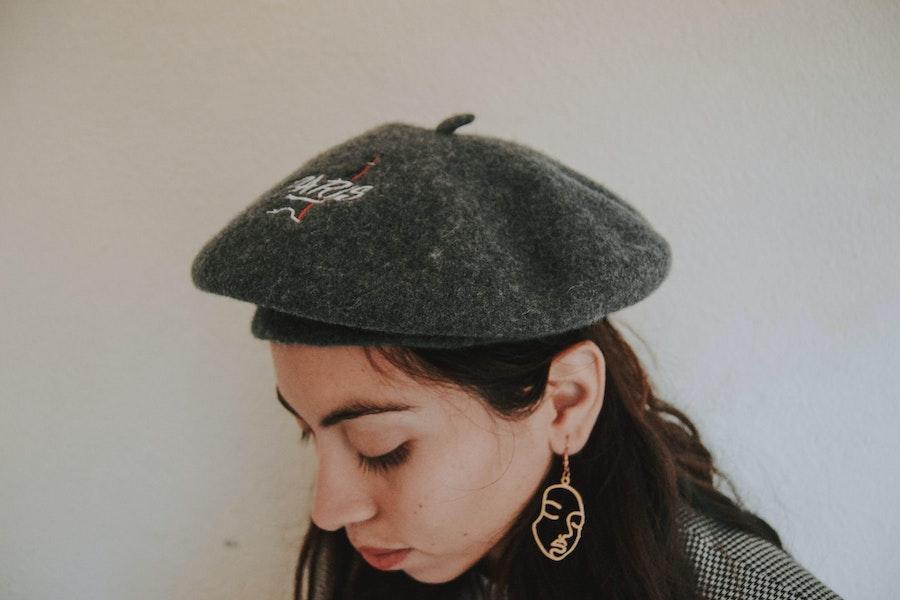 Woman wearing a grey beret and looking down
