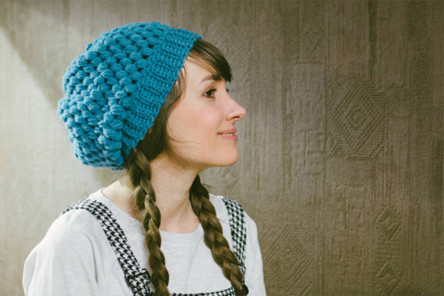 Woman wearing warm blue crochet beanie with braids