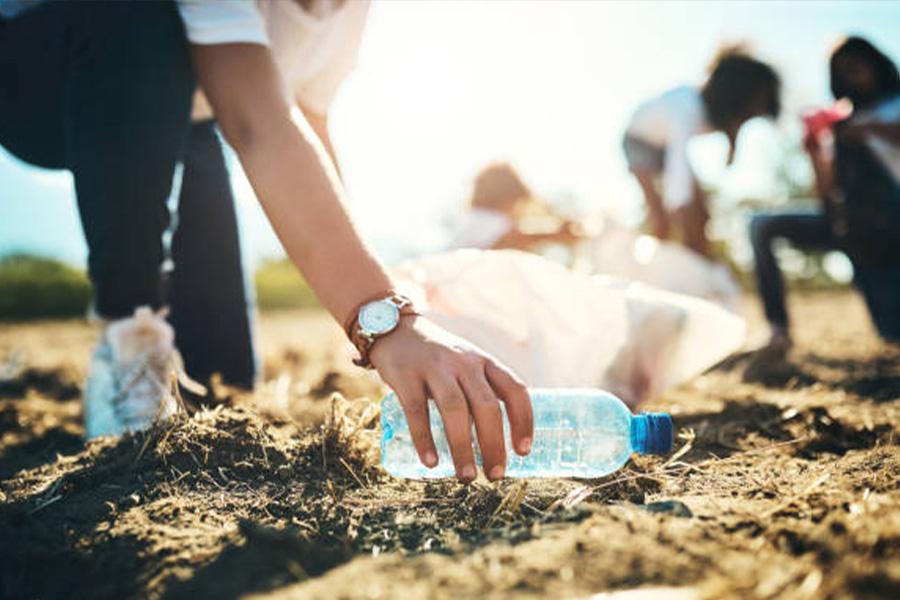 Worker collecting a plastic bottle from the ground