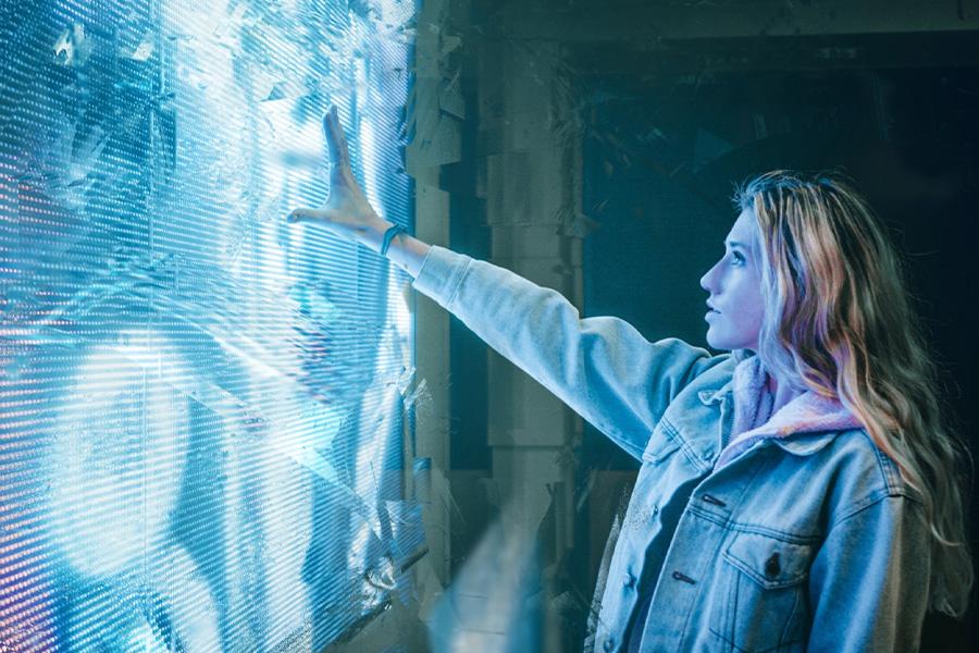 Young woman touching futuristic interface projected on wall