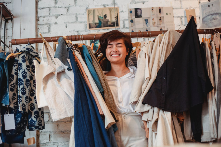A happy woman holding various clothing items