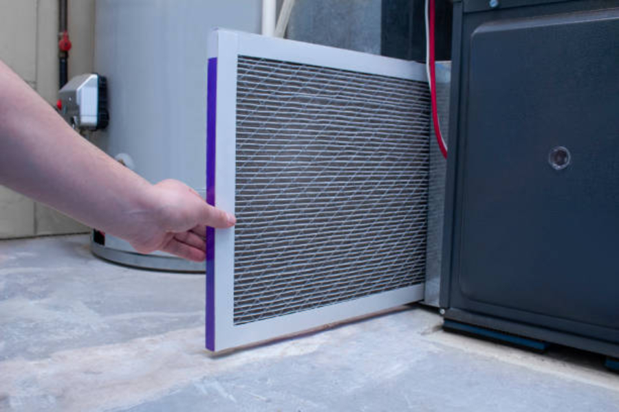 A man changing an air filter on a furnace