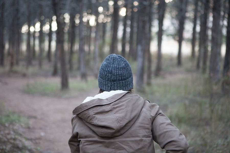 a person wearing cuffed beanie and running amid woods