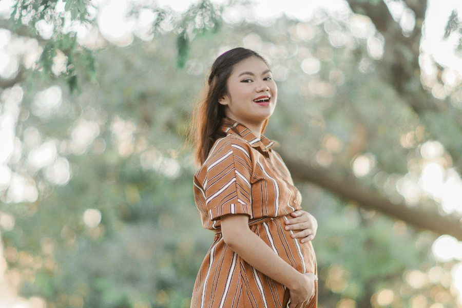 A pregnant woman in a striped shirt dress