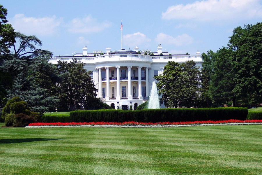 A wide grass garden with the U.S. white house in the background