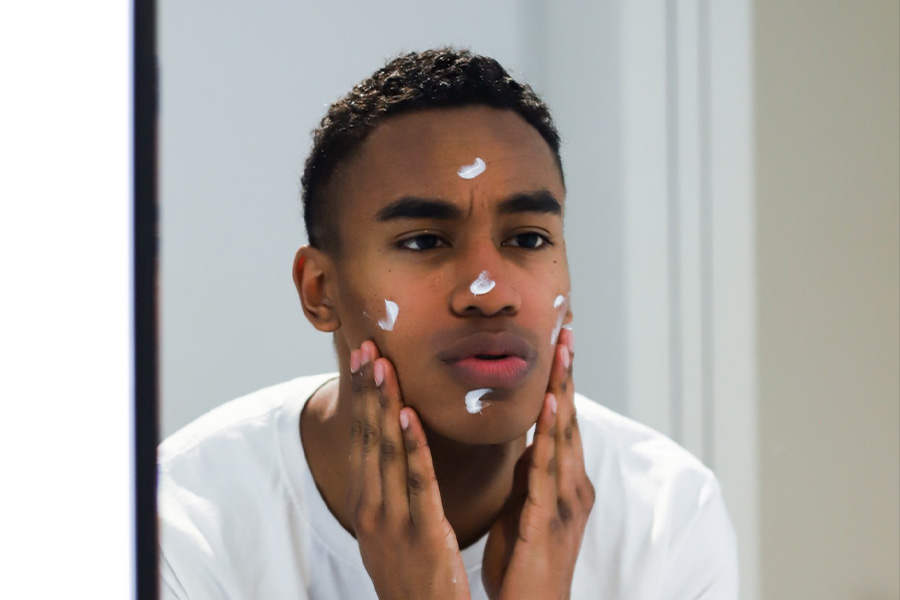 A young man putting on skincare products