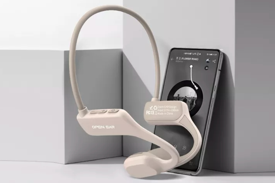 beige bone conduction headphones standing in front of a smartphone