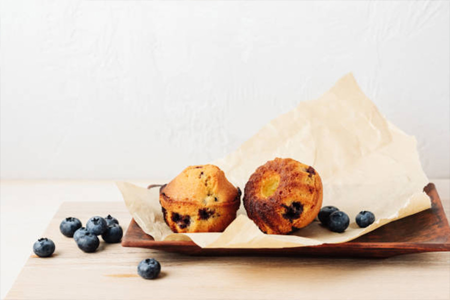 Blueberry muffins on a baking tray with parchment paper