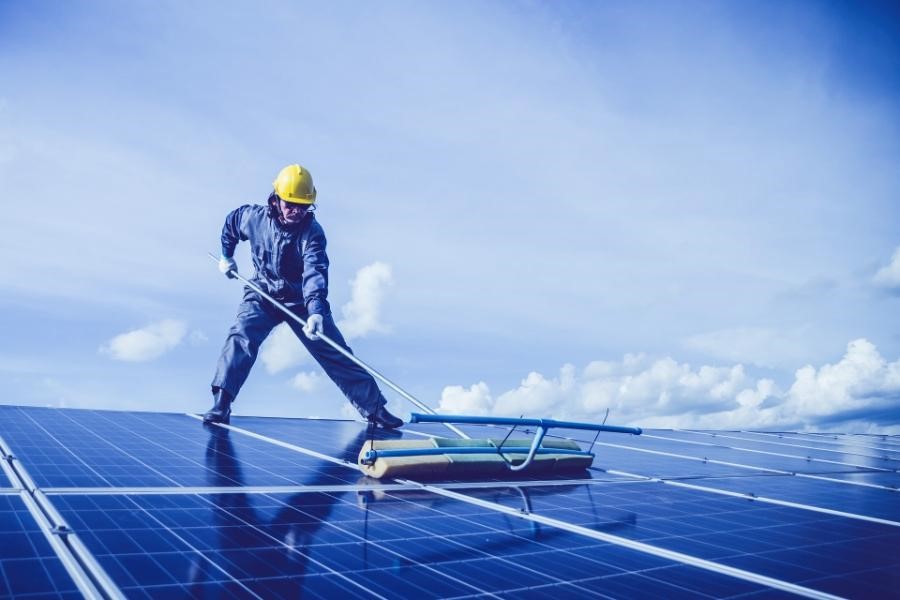 Man cleaning linked blue solar modules