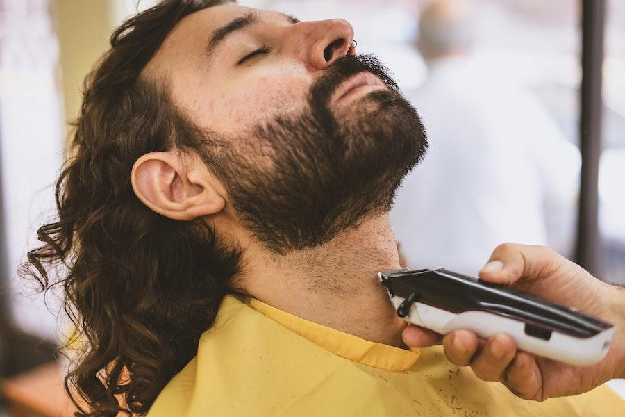 Man getting a beard trim from a cordless clipper