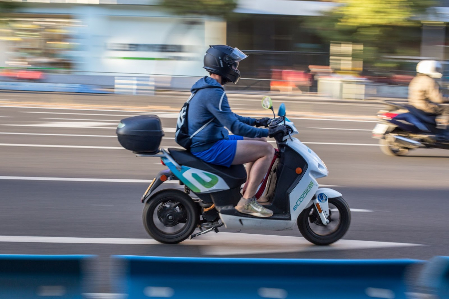 Man in blue jacket riding an electric motorcycle on road