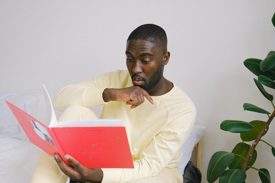 Man reading a red book while wearing yellow pajama