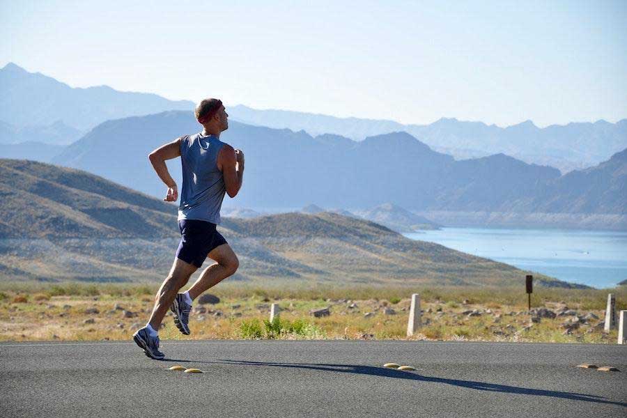 Man running in a blue tank top and black shorts