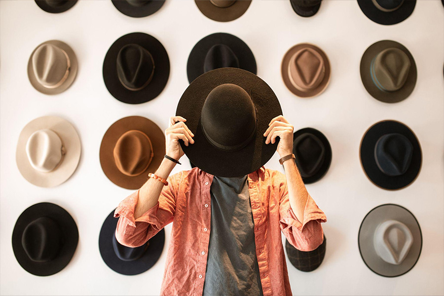 A man standing in a room full of fedora hats