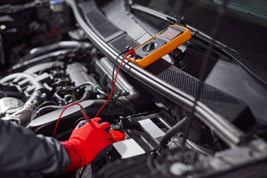 mechanic in protective gloves checking voltage of vehicle battery