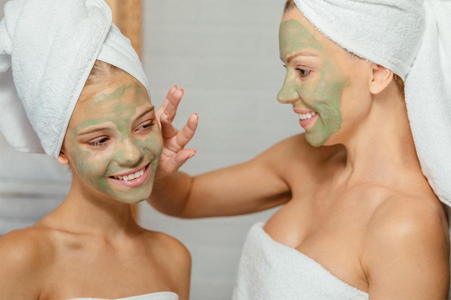 Mother and daughter applying organic beauty product