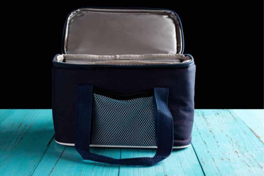 Navy blue soft shell cooler on bright blue wooden table