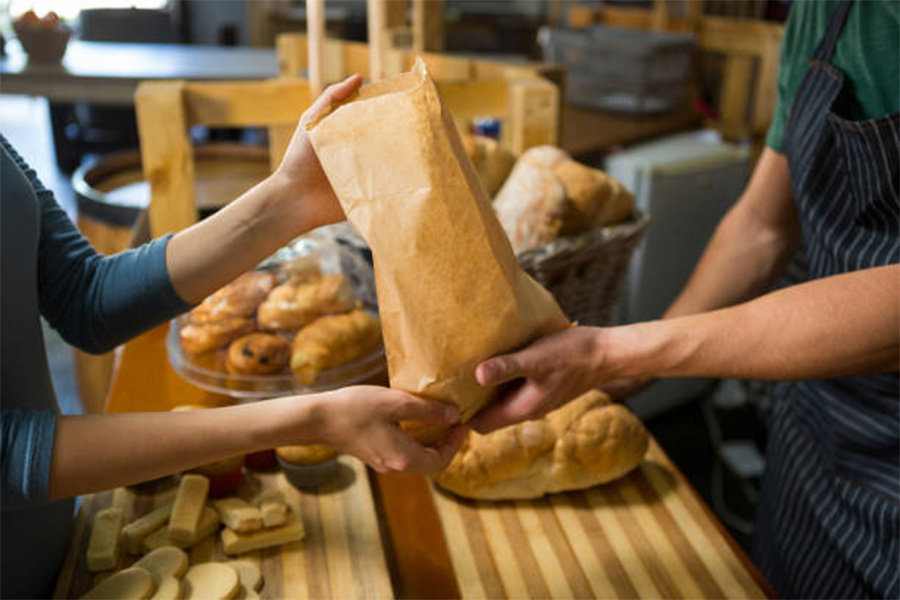 Person in bakery handing goods to customer over counter