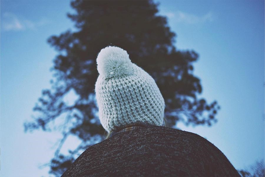 Person wearing a knitted beanie with a pom-pom