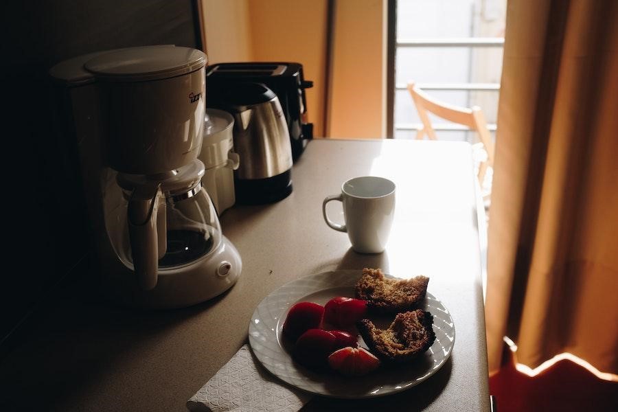 Single-serve coffee machine near a cup and breakfast