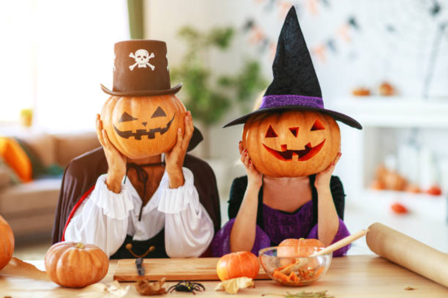 Two people holding up pumpkins to their face wearing hats